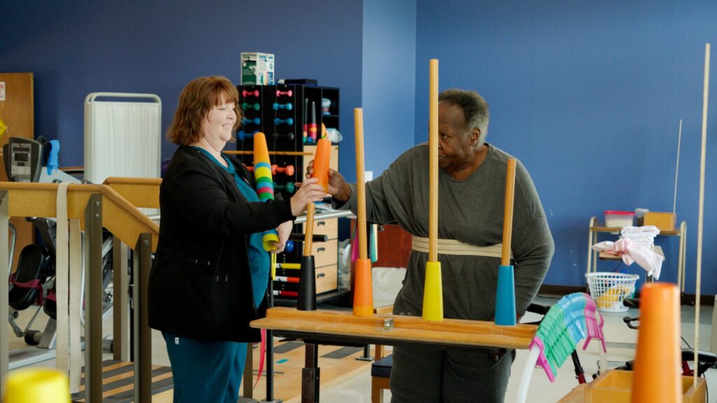 A man and nurse in a therapy room for a short term rehab facility