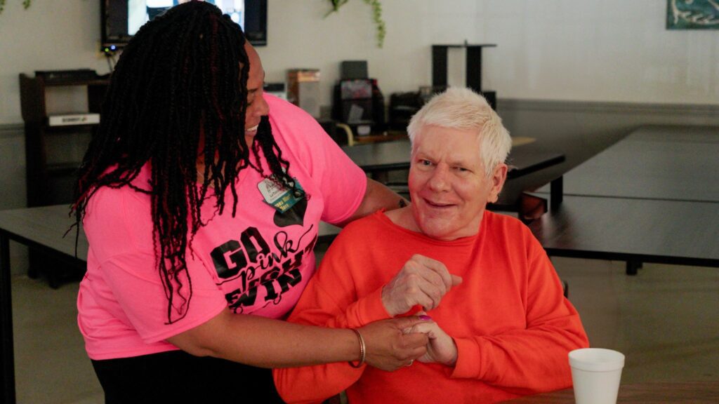 A man and nurse smile at each other at a long term care facility