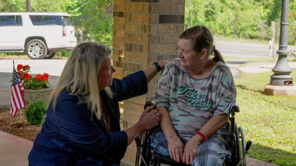 A woman utilizing the respite care service is smiling and speaking to a staff worker at a skilled nursing facility nursing home