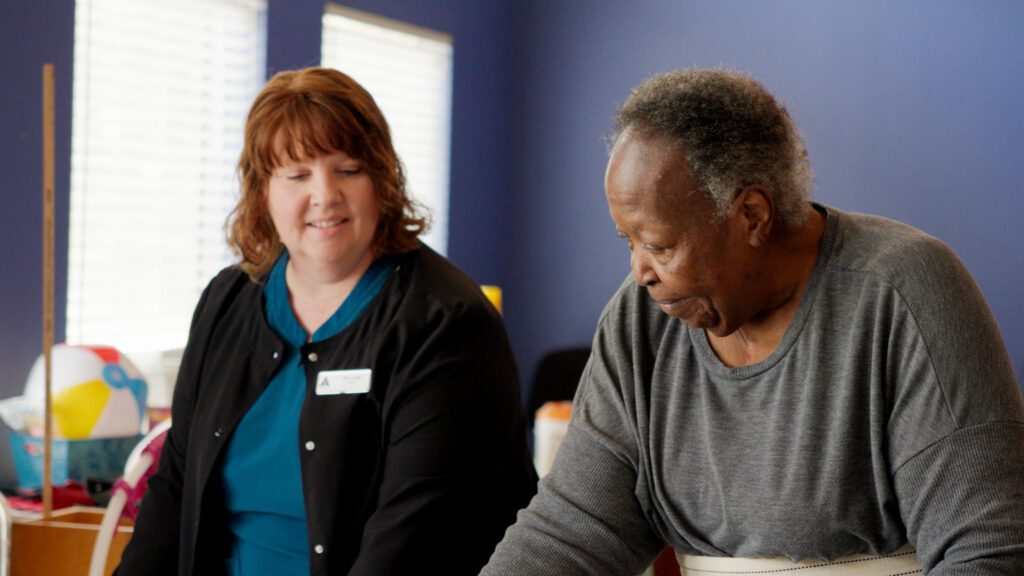 A woman and nurse smiling at each other at a skilled nursing facility